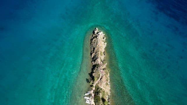 Small rocky island surrounded by clear blue lake