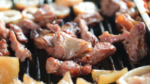Grilled pork parts sizzling on a restaurant's barbecue grill