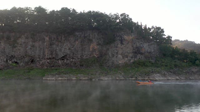 Boat speeding along the river with misty cliffs in the background