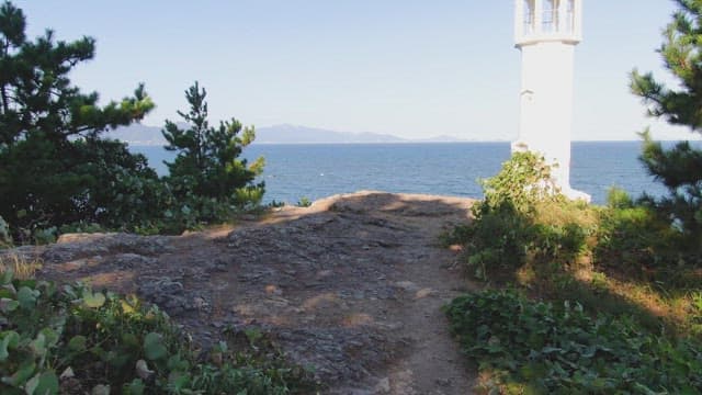Lighthouse by the sea with distant mountains