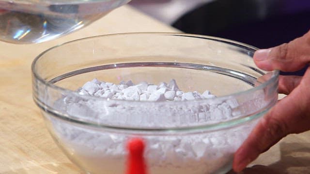 Hand pouring water into starch flour