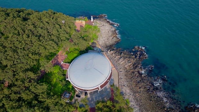 Buildings on Dongbaekseom Island surrounded by forests and rocky beaches