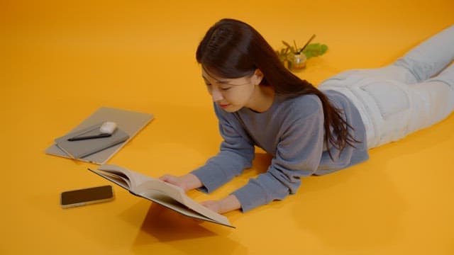 Woman reading a book while lying on her stomach in a bright room