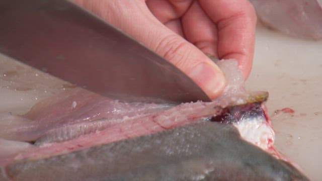 Fresh fish being prepared with a knife on a cutting board