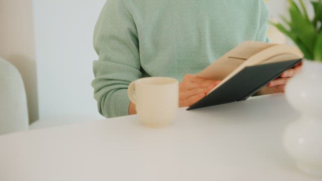 Person Reading a Book at a Table