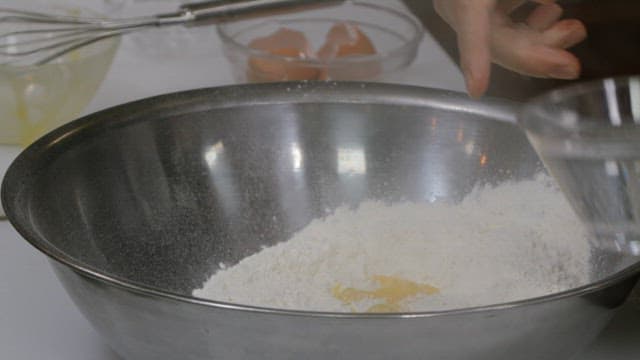 Pouring water into flour to make dough