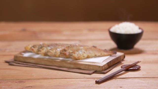 Grilled corvina and steamed rice served on a wooden table