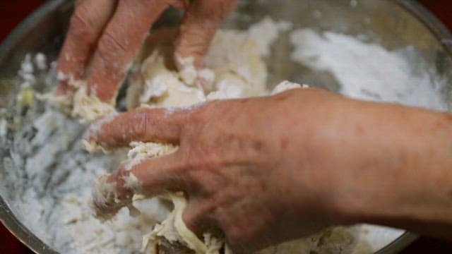 Hand kneading dough in a metal bowl