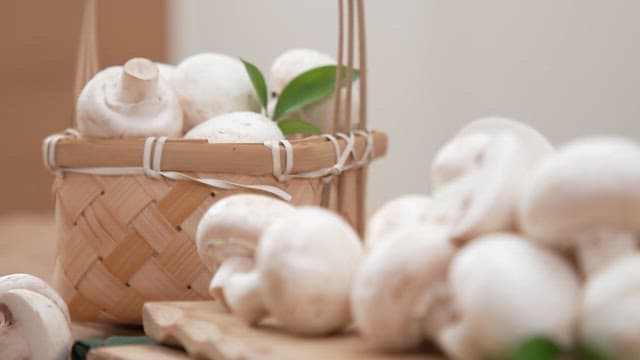 Fresh white mushrooms in a wooden basket