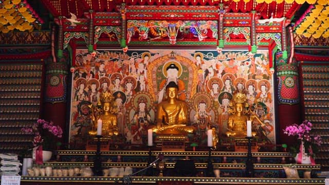 Temple interior decorated with Buddhist statues, colorful paintings, and wish papers