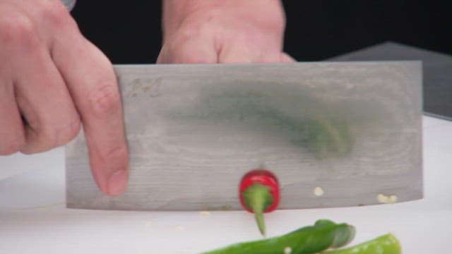 Slicing a red chili pepper on a white cutting board