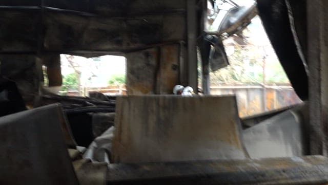 Police investigators inspect a burnt building wreckage.