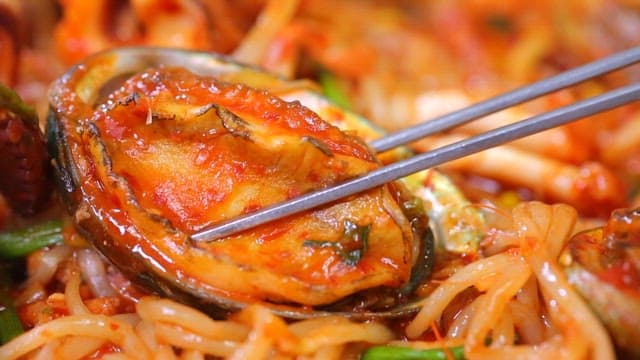 Chopsticks holding abalone in spicy braised seafood