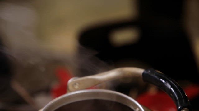 Putting fish cake skewers into a kettle with boiling broth