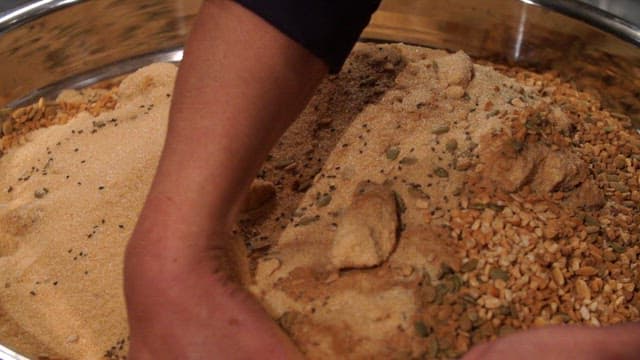 Mixing sugar with nuts and seeds in a bowl