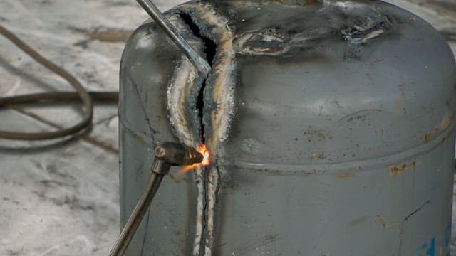 Cutting open a gas cylinder with a welding torch in a workshop