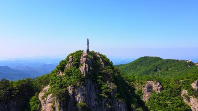 Mountain landscape with a tower commemorating the summit under a clear sky