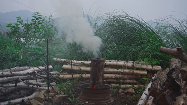 Smoke rising from a firewood in a rural setting