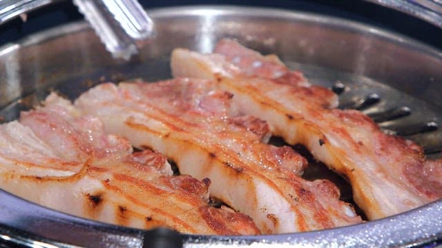 Grilled pork belly sizzling on a grill