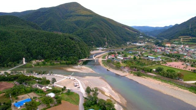 Scenic view of a serene countryside with a crescent-shaped bridge spanning over a peaceful river