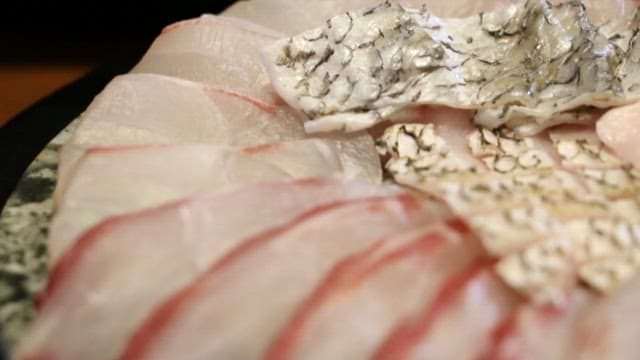 Fresh sashimi pieces being dipped in sauce