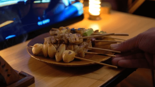 Bowl of skewers arranged on a plate in a wooden table with warm lighting