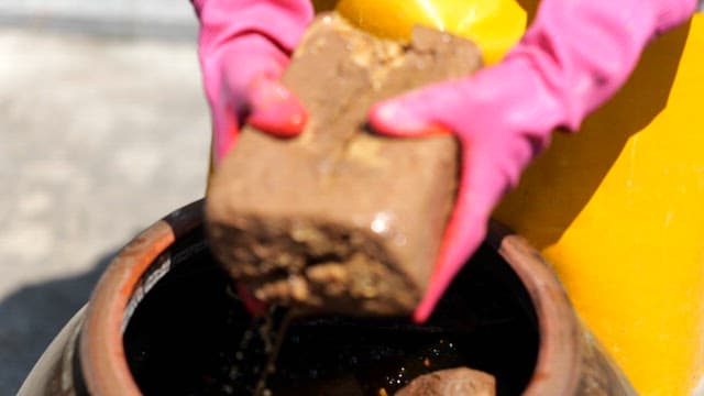 Taking out fermented soybean bricks from a crock pot