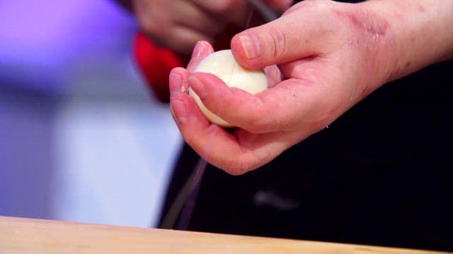 Chef slicing a peeled boiled egg
