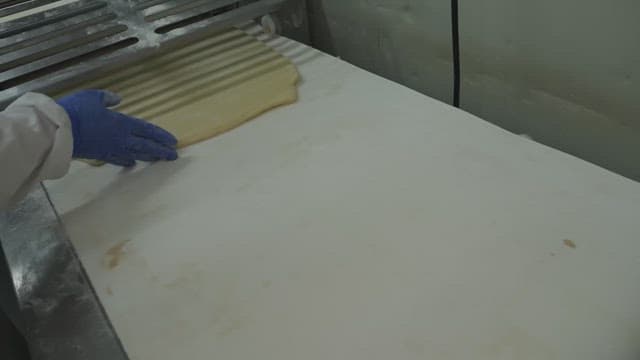 Person using a machine to prepare dough in a factory kitchen