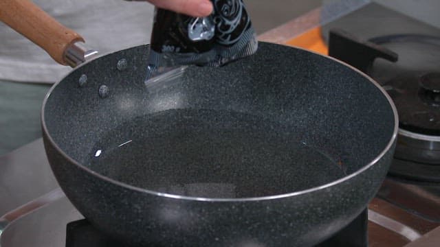 Pouring the Chunjang Sauce into the Pan on the Gas Stove