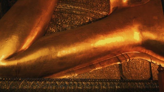 Upper body of a giant golden Buddha statue inside the temple