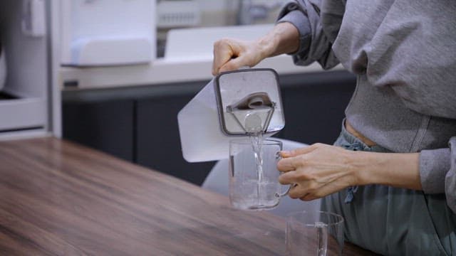 Pouring water into a glass in a kitchen
