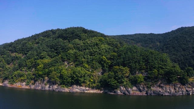 Lush green mountains by a serene river under a clear sky