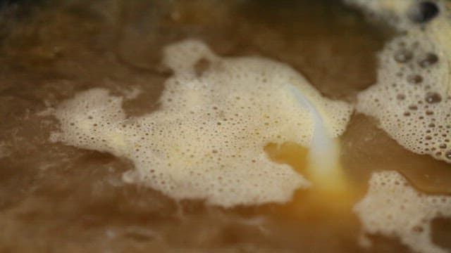 Udon noodles boiling in a pot of broth