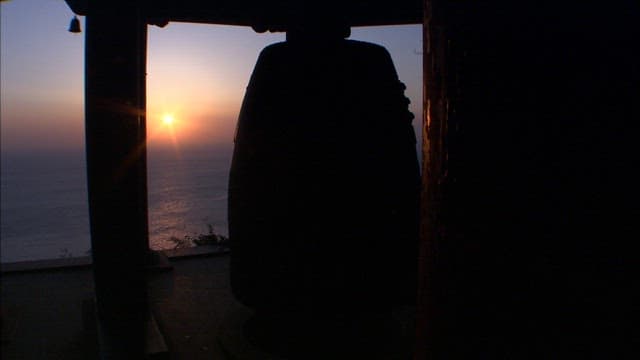 Sunset behind a bell at a seaside temple