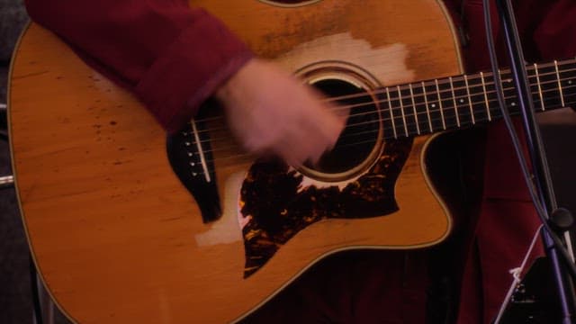 Street musician playing a acoustic guitar at night in winter