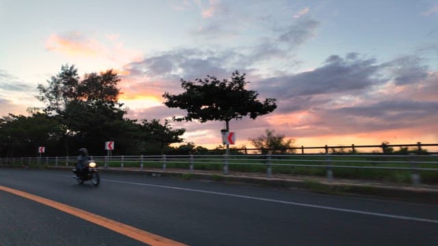 Motorcycle and car on a scenic road at sunset