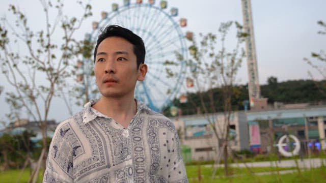 Man walking in the park next to the ferris wheel
