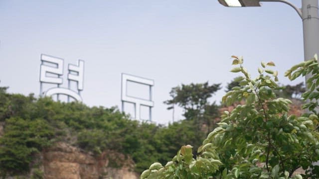 Coastal area with Baeknyeongdo Island sign on cliff on a cloudy day
