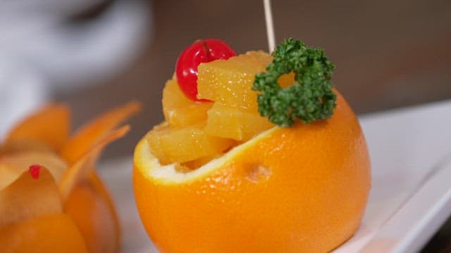 Fresh fruit dessert with decorative cherries and greens on a plate.