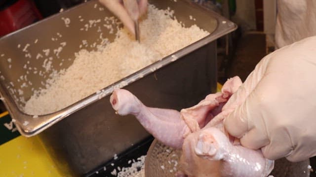 Rice being generously filled into raw chicken