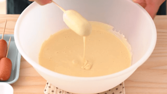 Scene of coating batter on powdered sausages