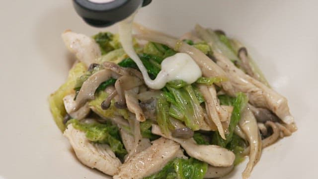 Cream sauce being poured over stir-fried chicken and vegetables