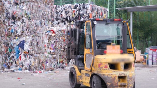 Recycling facility with forklift moving piles of waste outdoors