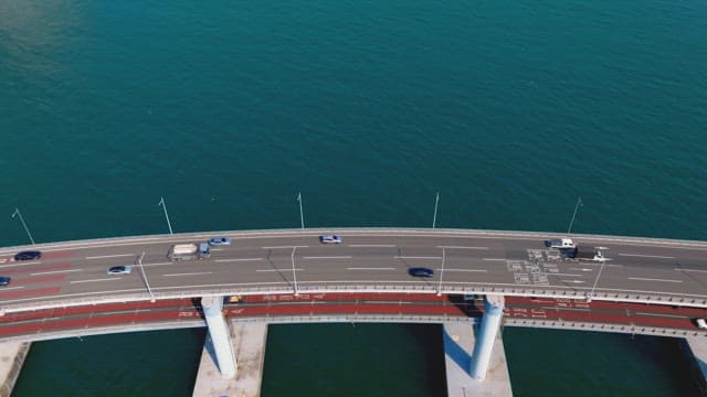 Aerial view of cars driving on a bridge over the blue ocean