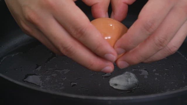Cracking a fresh egg into a hot frying pan