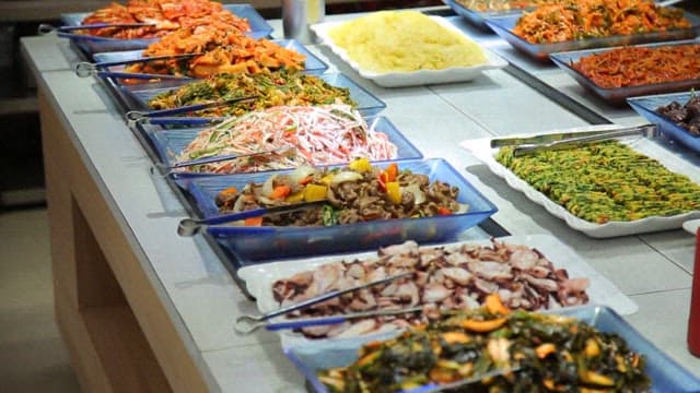 Variety of foods such as salads, vegetables, and meats displayed on a buffet
