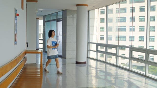 Woman walking down a bright hallway