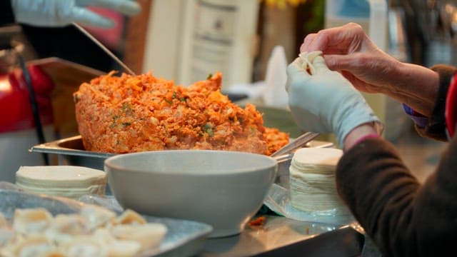 Hands making dumplings with kimchi filling