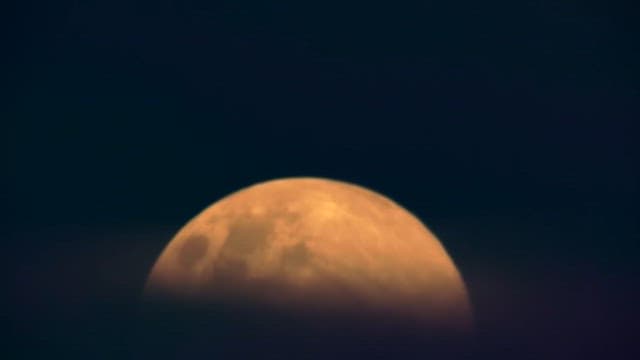 Close-up View of a Moon Rising on a Dark Night